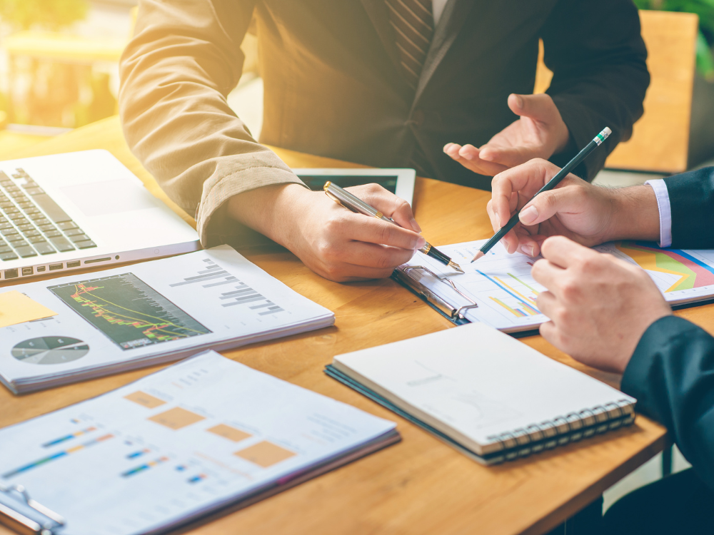 A desk with people working over business proposals and reports